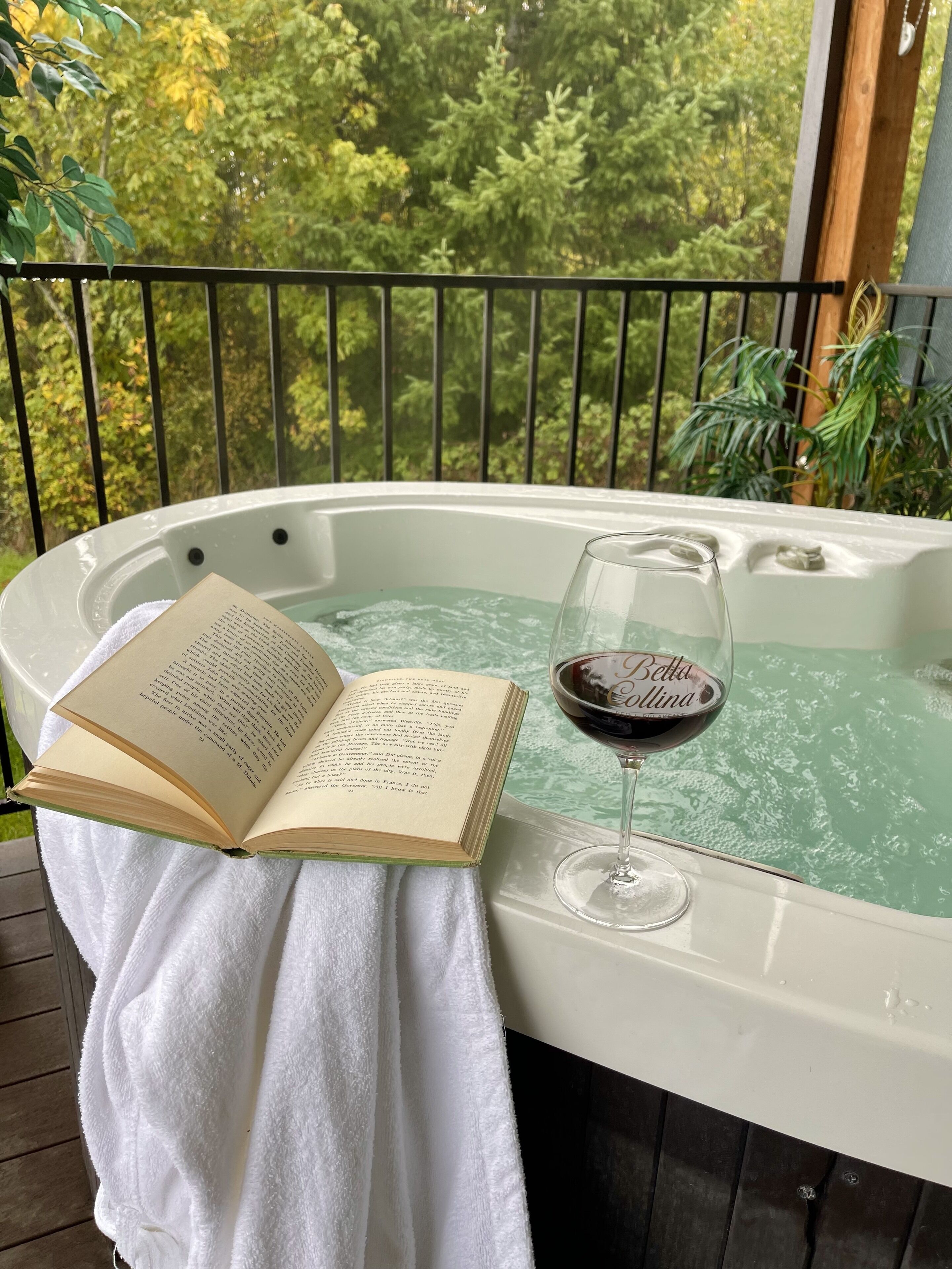 Ein Whirlpool mit einem Buch und einem Glas Wein auf einem weißen Handtuch.
