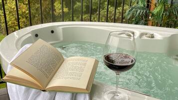 Ein Whirlpool mit einem Buch und einem Glas Wein auf einem weißen Handtuch.