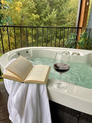 Un bain à remous, un livre et un verre de vin, le tout posé sur une serviette blanche.