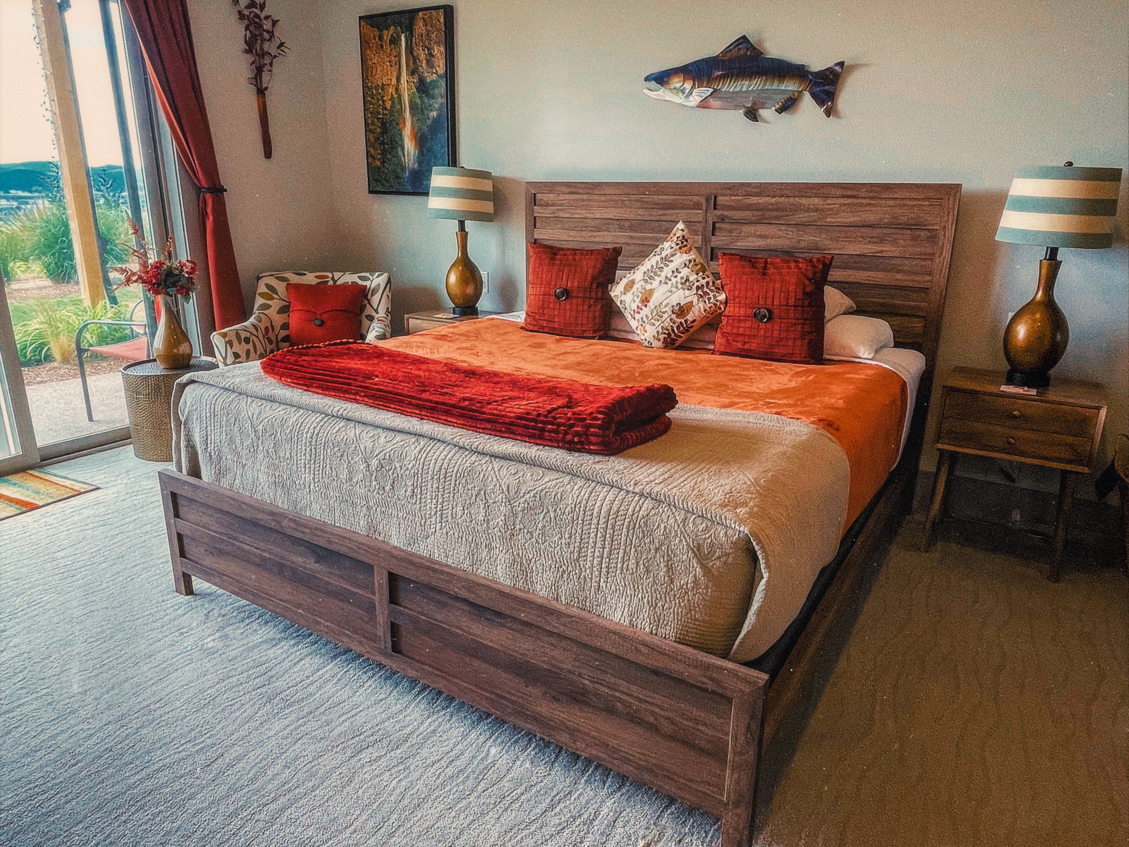 Una cama grande con estructura de madera, dos mesitas de noche y una decoración de peces en la pared.