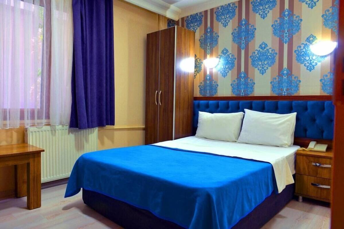 A bedroom with a bed, a wooden wardrobe, a bedside table, and a nightstand.
