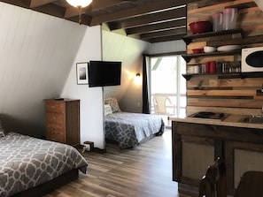 A compact room with two beds, a TV, a kitchenette, and a sliding glass door leading to an outdoor area. - Calm Waters Cabin Resort (Branson)