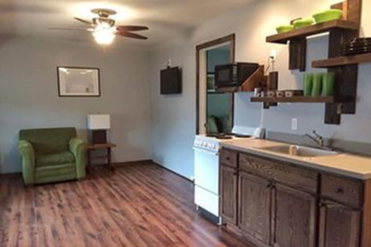 A compact kitchen with wooden cabinets, a microwave, and a sink.