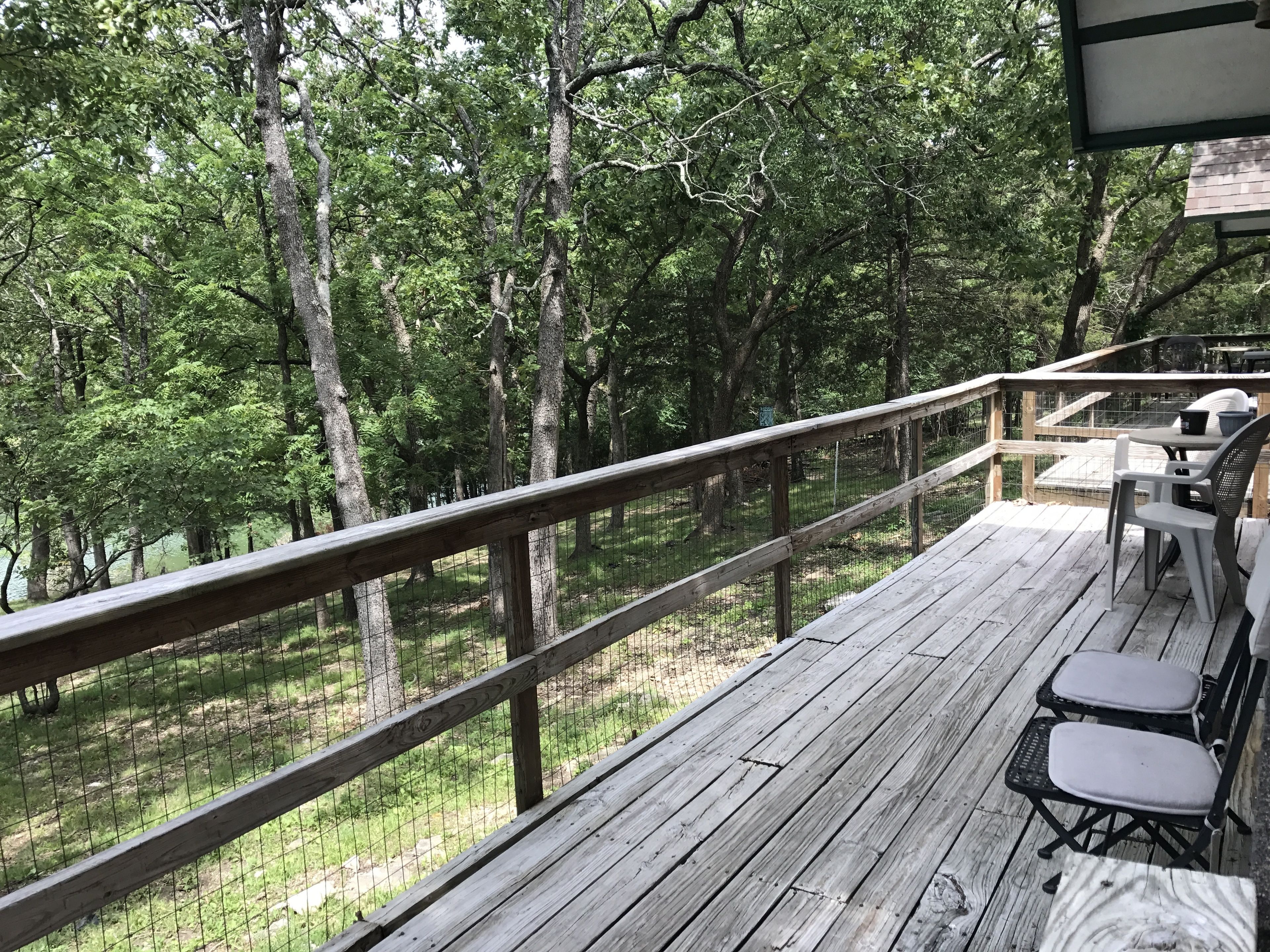 A wooden deck with a railing overlooking a forested area.