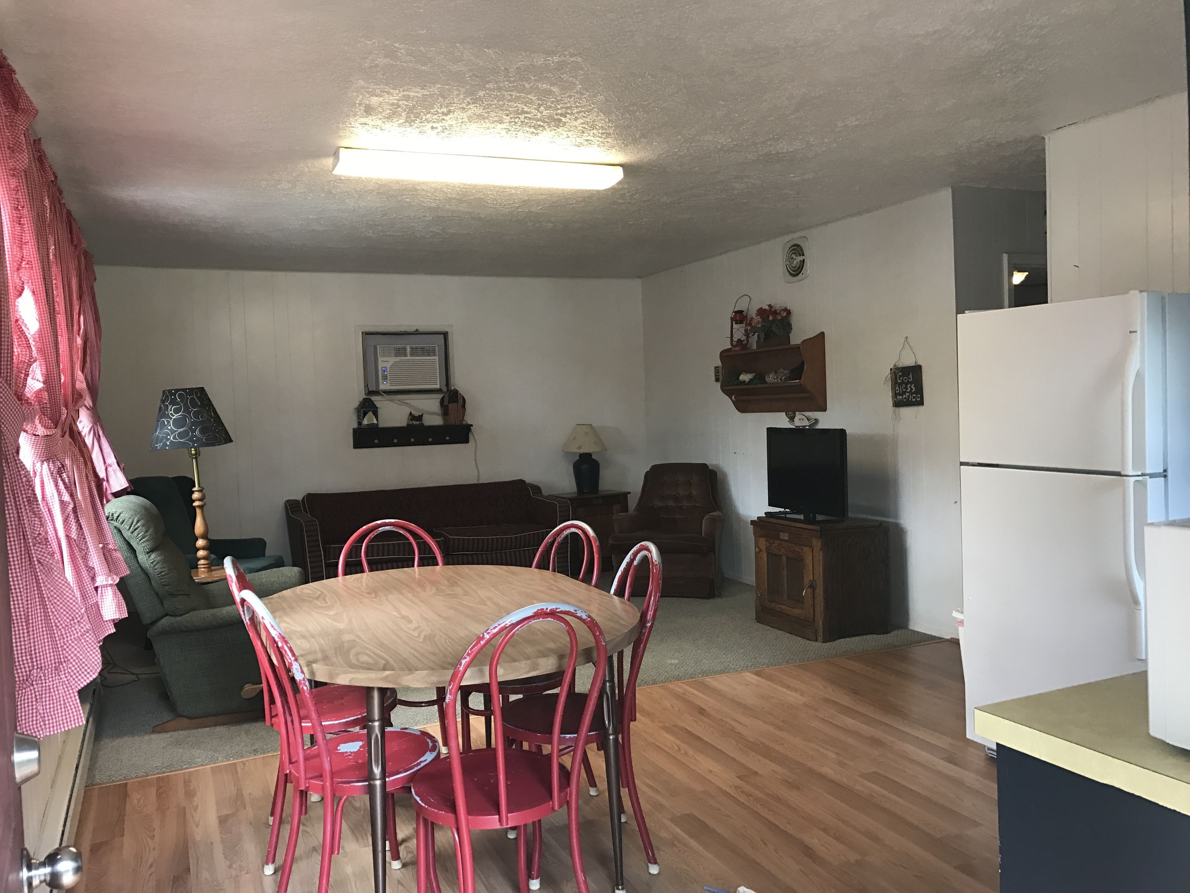 A compact living space with a dining area, a sofa, a television, and a refrigerator.