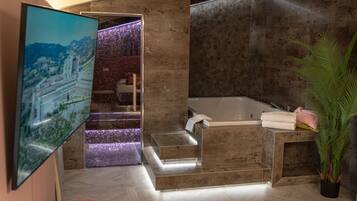 Une salle de bain moderne dotée d’une grande baignoire, d’un espace douche et d’un escalier apparent menant à un balcon.
