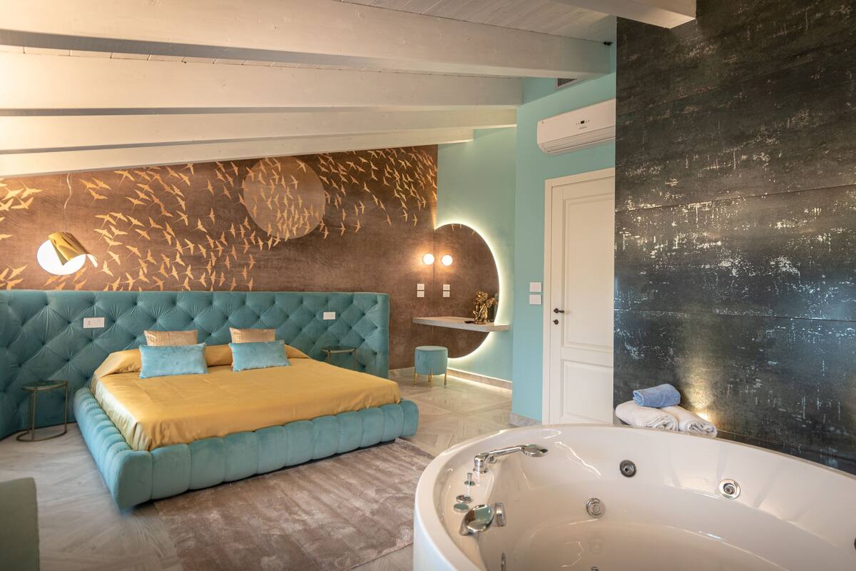 Quarto moderno com uma cama grande, uma banheira e uma parede com um mural de aves.
