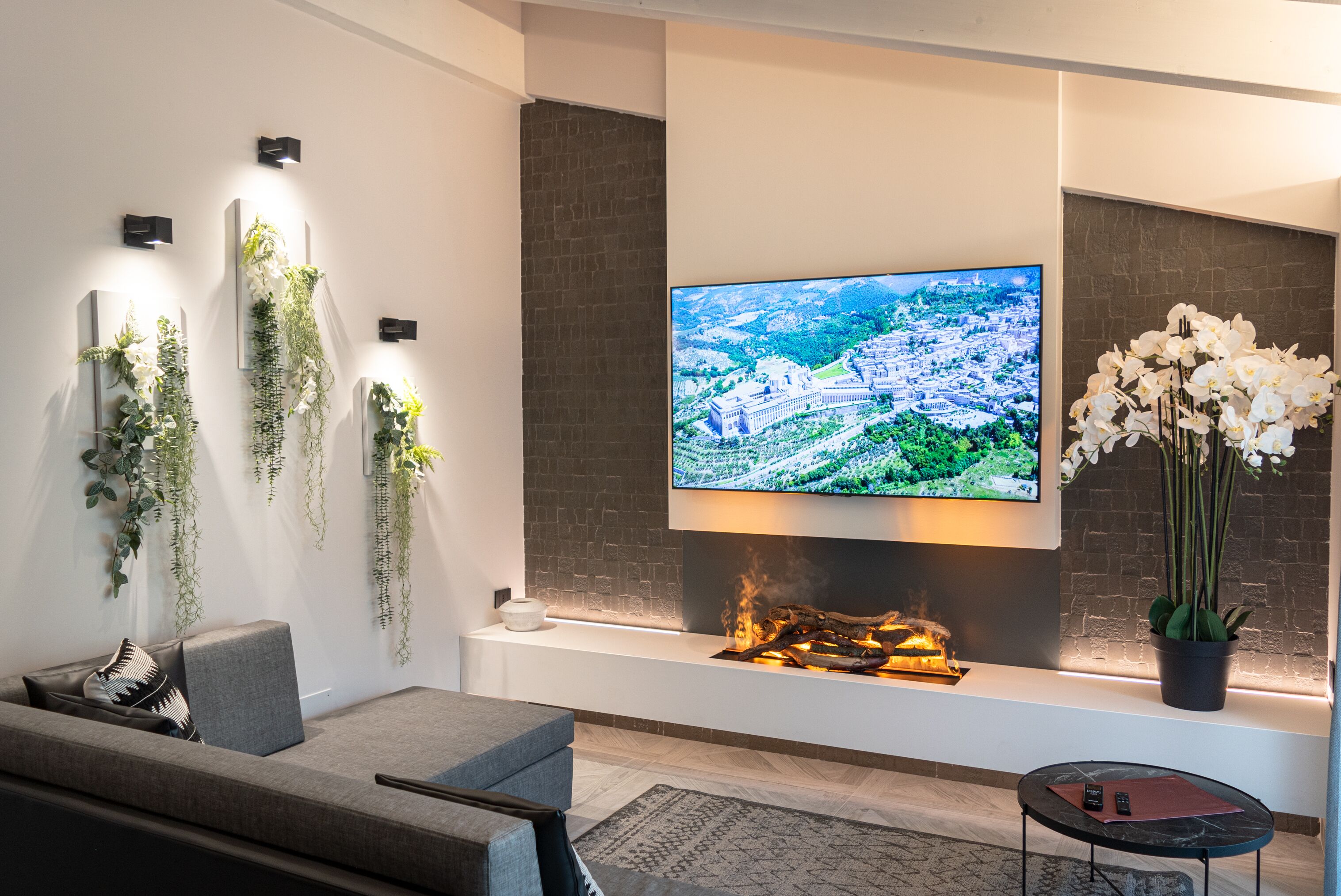 Una sala de estar moderna con un televisor de pantalla plana, una chimenea y plantas decorativas.