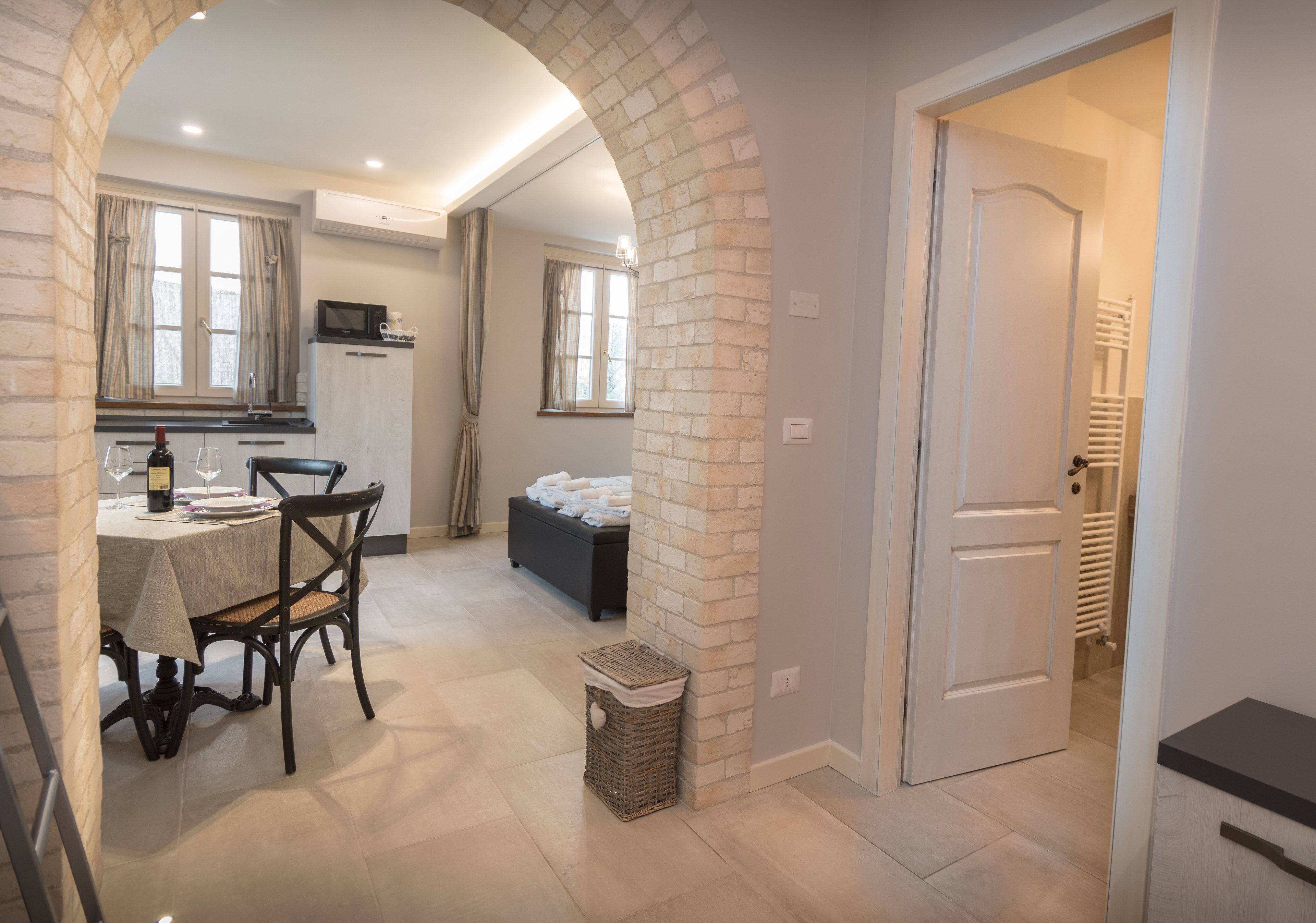 A dining area with a table, chairs, and a basket. There is a doorway leading to another room.