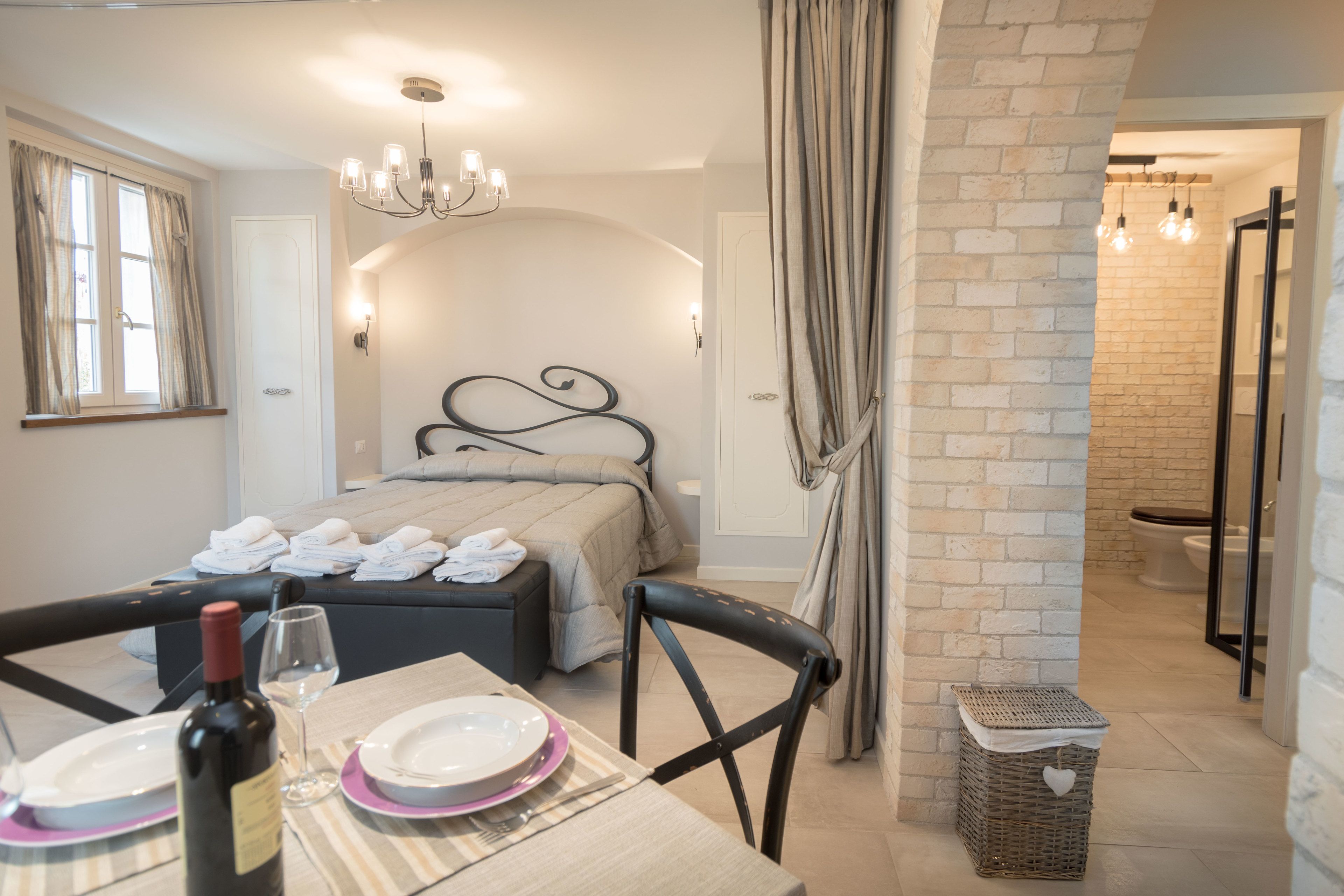 A neatly arranged bedroom with a bed, bedside table, and a dining area with a table set for two.