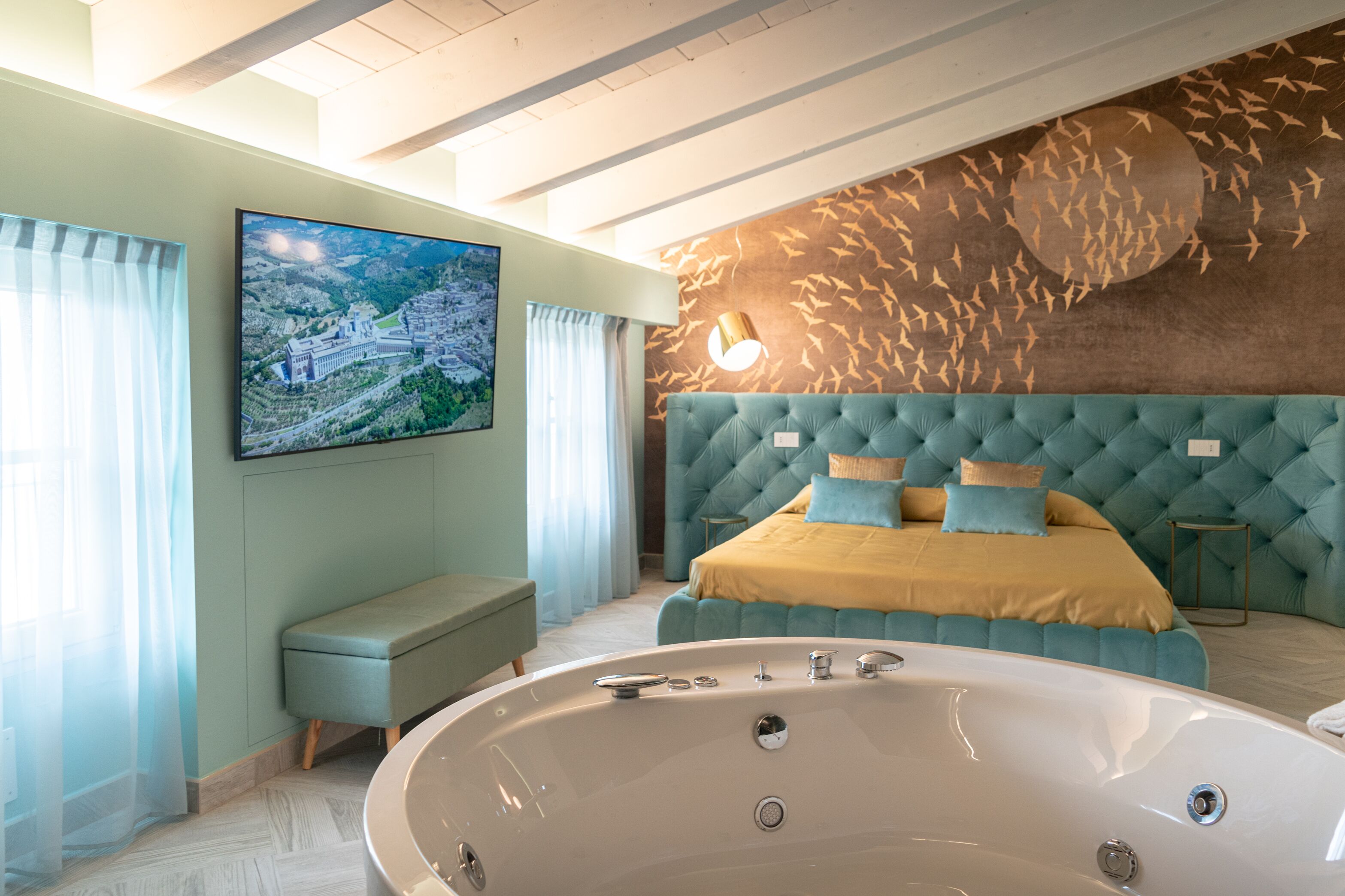 A modern bedroom with a large bed, a bathtub, and a cityscape painting on the wall.
