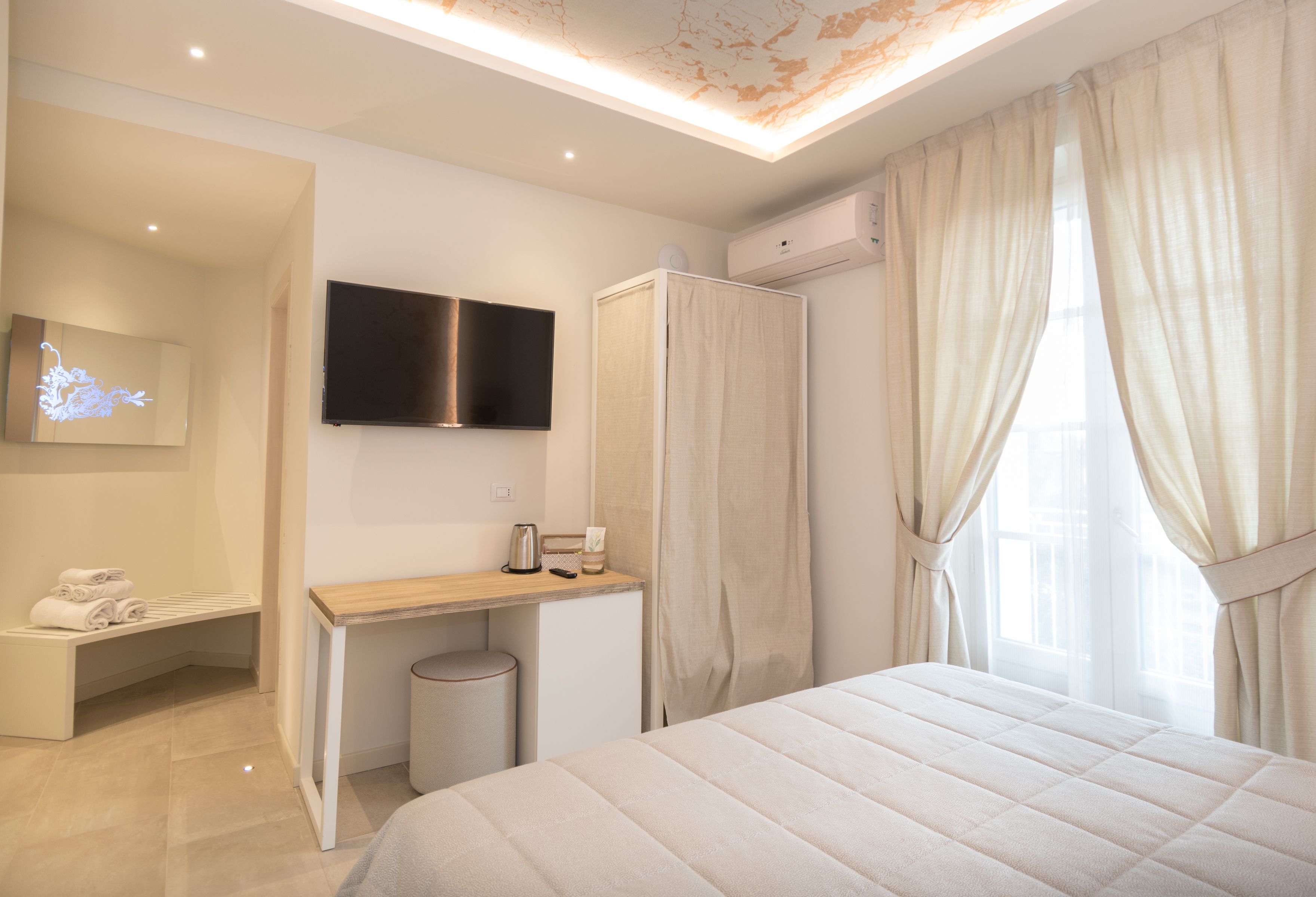 A hotel room with a bed, a desk, a TV, a wardrobe, and a bathroom.