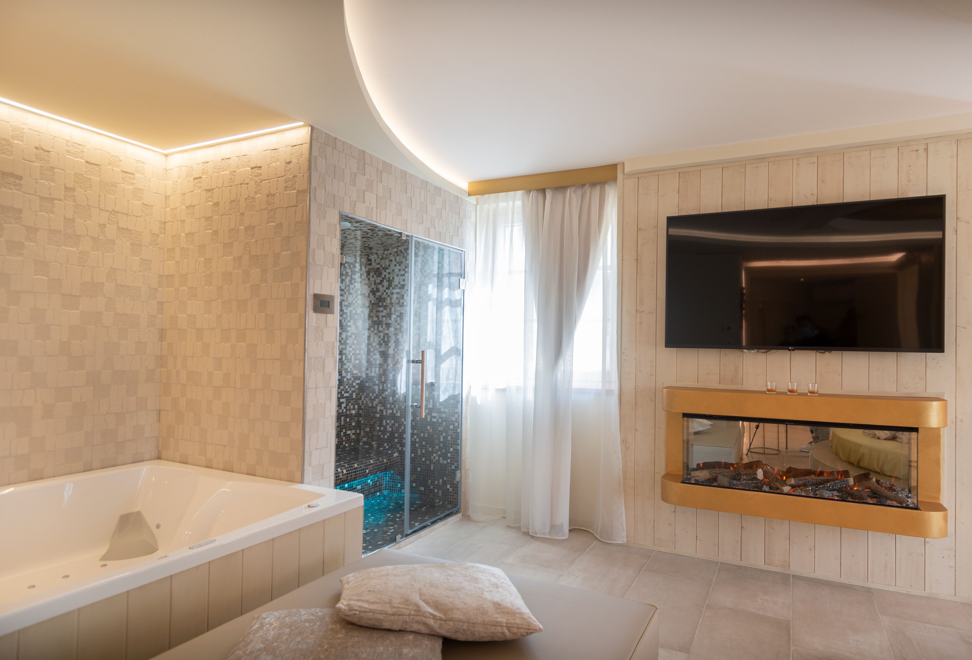 Une salle de bain moderne dotée d’une baignoire, d’une douche à parois de verre, d’un téléviseur à écran plat fixé au mur et d’une cheminée intégrée.