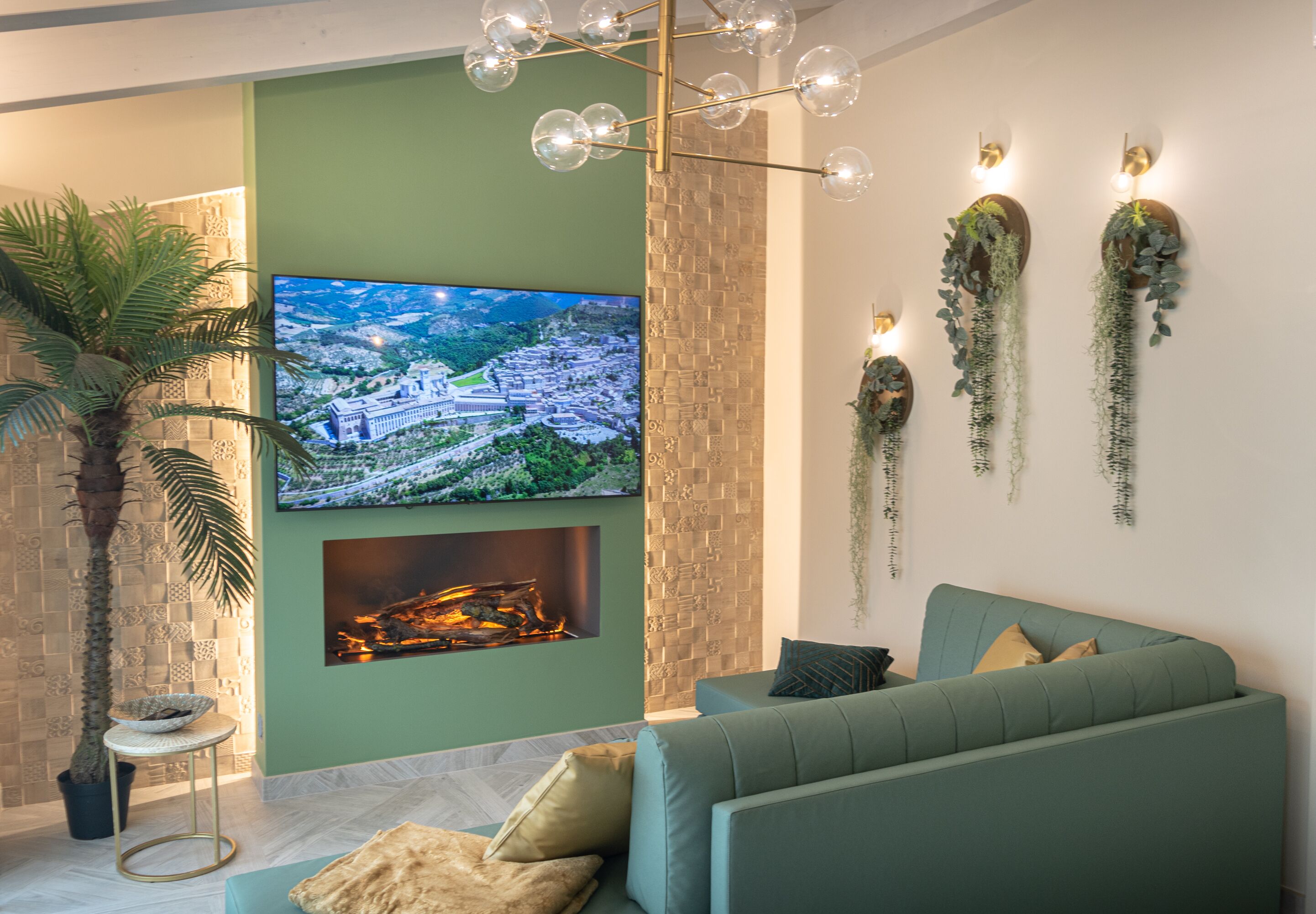 A modern living room with a green sofa, a flat-screen TV, a fireplace, and decorative wall plants.