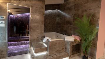 Ein modernes Badezimmer mit einer großen Badewanne, einem Spiegel und einer Topfpflanze.