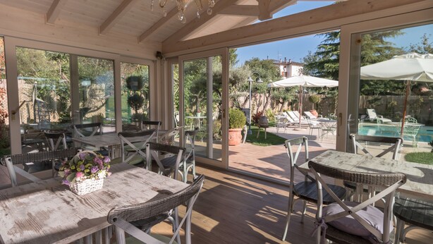 An outdoor patio area with wicker furniture, large windows, and a view of a swimming pool.