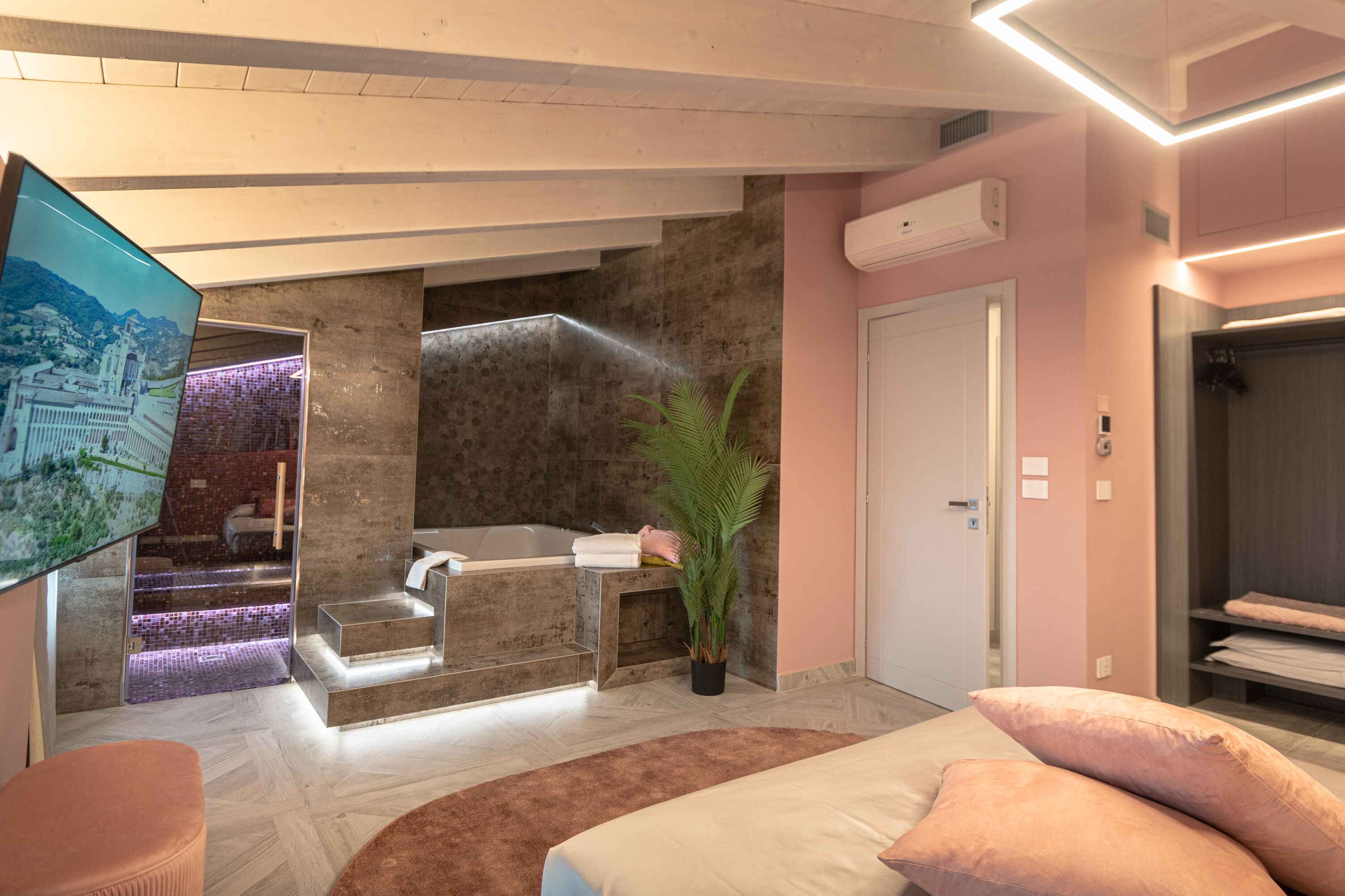 Ein modernes Badezimmer mit einer Badewanne, einer Dusche und einem Waschbecken. Eine Topfpflanze und ein großer Spiegel sind vorhanden.