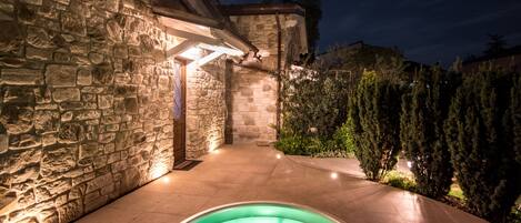 Un bâtiment en pierre avec un jacuzzi en premier plan.