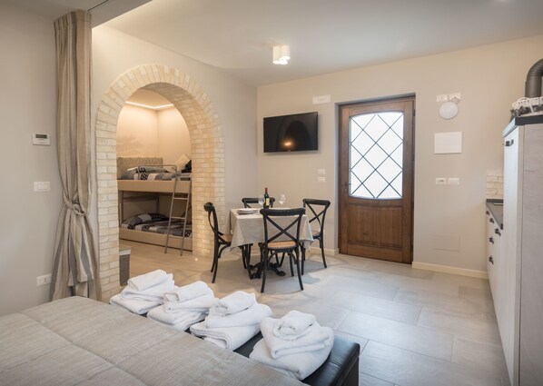 Habitación de hotel con cama, una mesa con sillas, televisor y ventana con vistas.