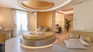 A modern bedroom with a circular bed, a sofa, and a desk.
