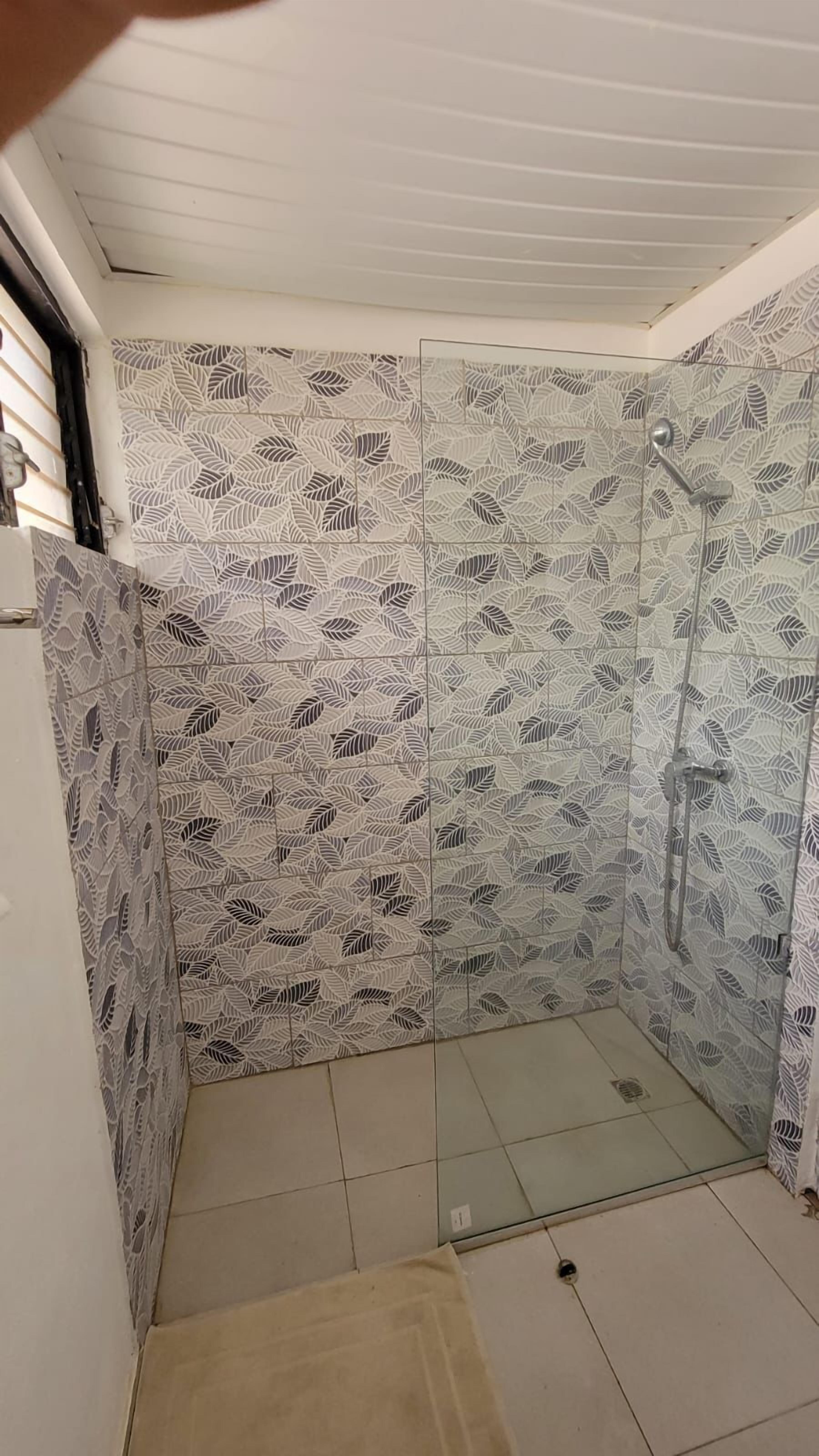 A shower area with patterned tiles and a glass door.