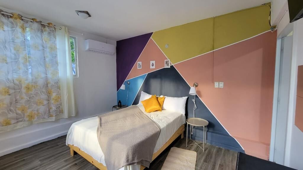 Een slaapkamer met een bed, nachtkastje, lamp en een raam met gordijnen.