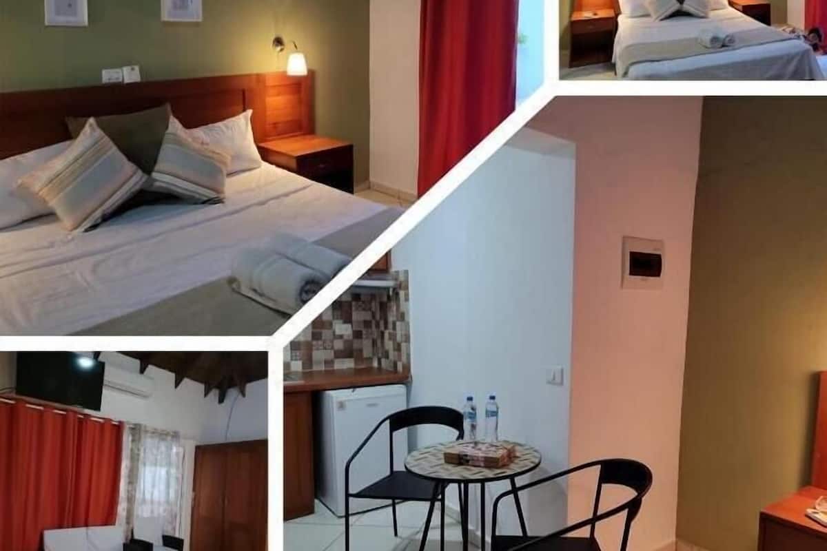 Ein Hotelzimmer mit Bett, Nachttischen, Schreibtisch, Stühlen und einer kleinen Küchenzeile.