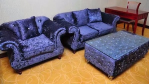 A room with a blue sofa set and a matching ottoman, a red table, and a patterned carpet. - Xining Xibai Hotel (Xining)