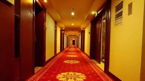 A hotel hallway with a red carpet and wooden doors. - Xining Xibai Hotel (Xining)