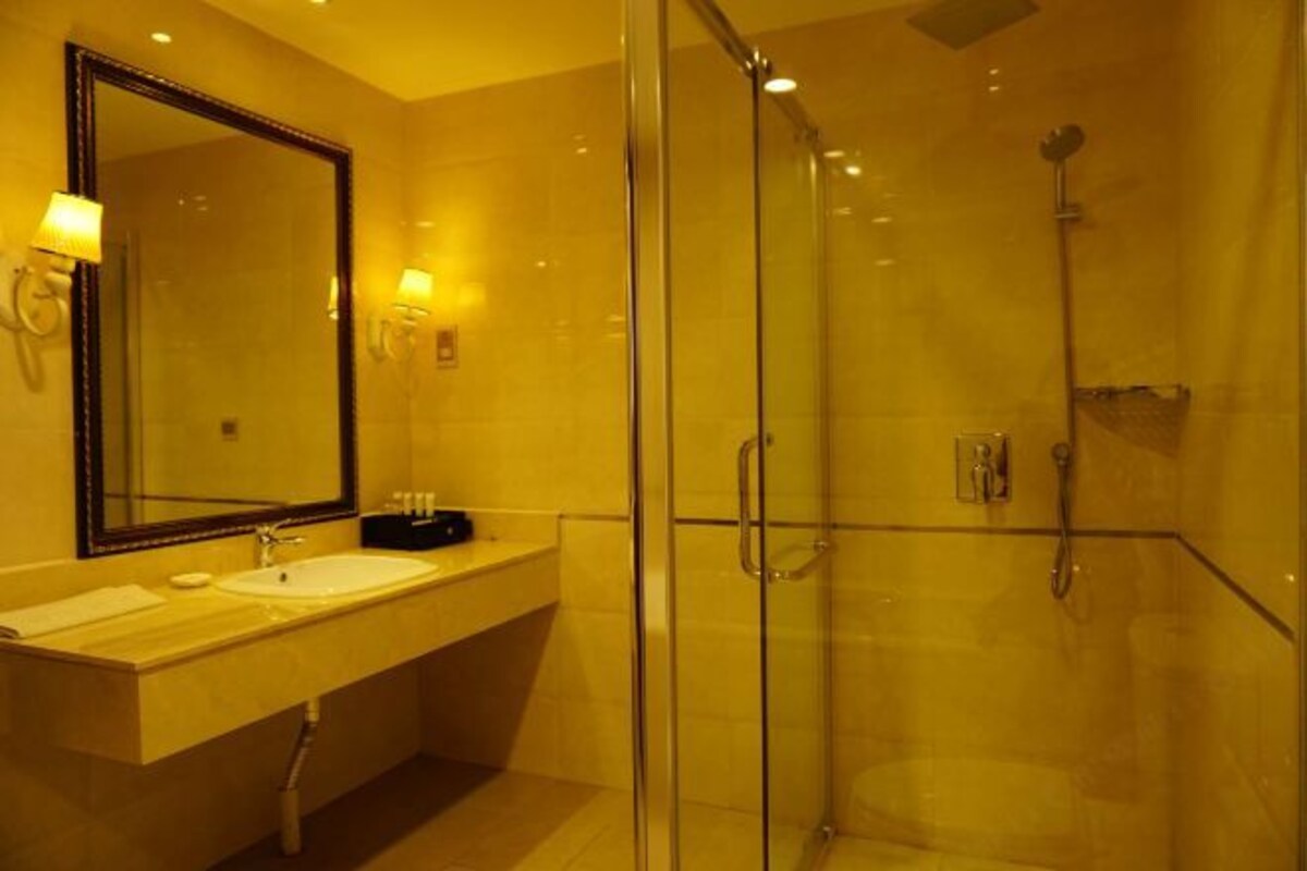 Une salle de bain moderne avec une douche à parois de verre, un grand miroir et un meuble-lavabo doté de deux vasques.