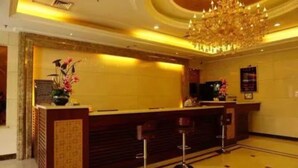 A reception area with a counter, a chandelier, and a decorative vase with flowers. - Xining Xibai Hotel (Xining)