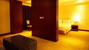A hotel room with a large bed, a nightstand, a desk, and a chair. - Xining Xibai Hotel (Xining)