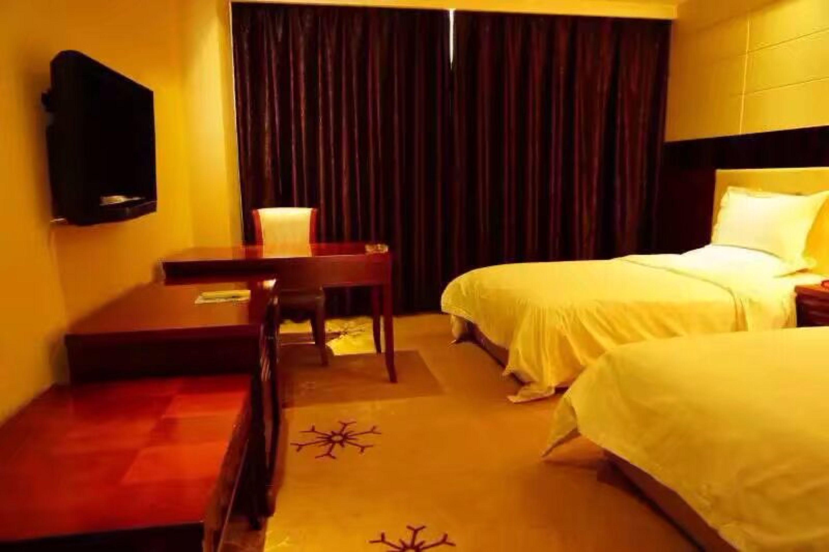 Ein Hotelzimmer mit zwei Betten, einem Schreibtisch, einem Stuhl, einem Fernseher und einem Vorhang.