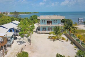 A two-story building with a light blue facade, a balcony, and a view of the ocean.