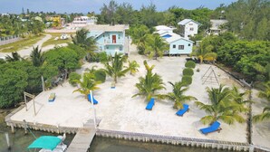 A beachfront property with a sandy beach, palm trees, and a dock.