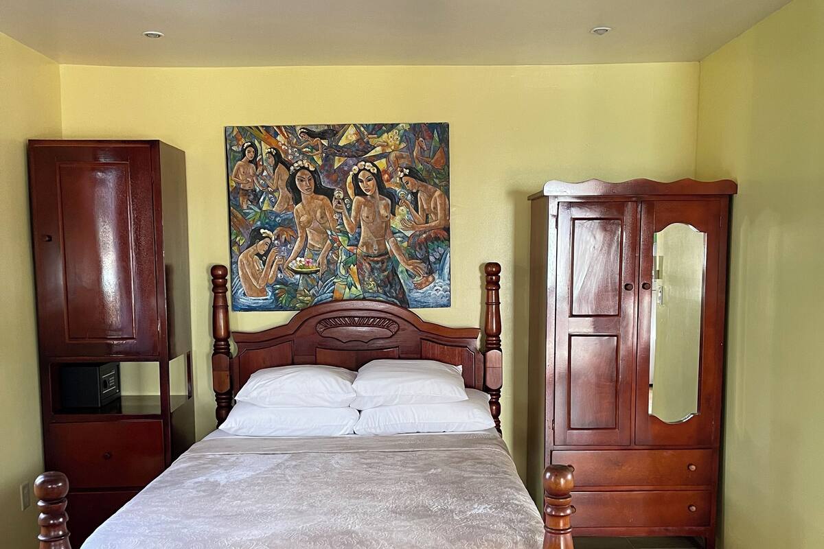 Un dormitorio con una cama de madera, un armario y un cuadro en la pared.