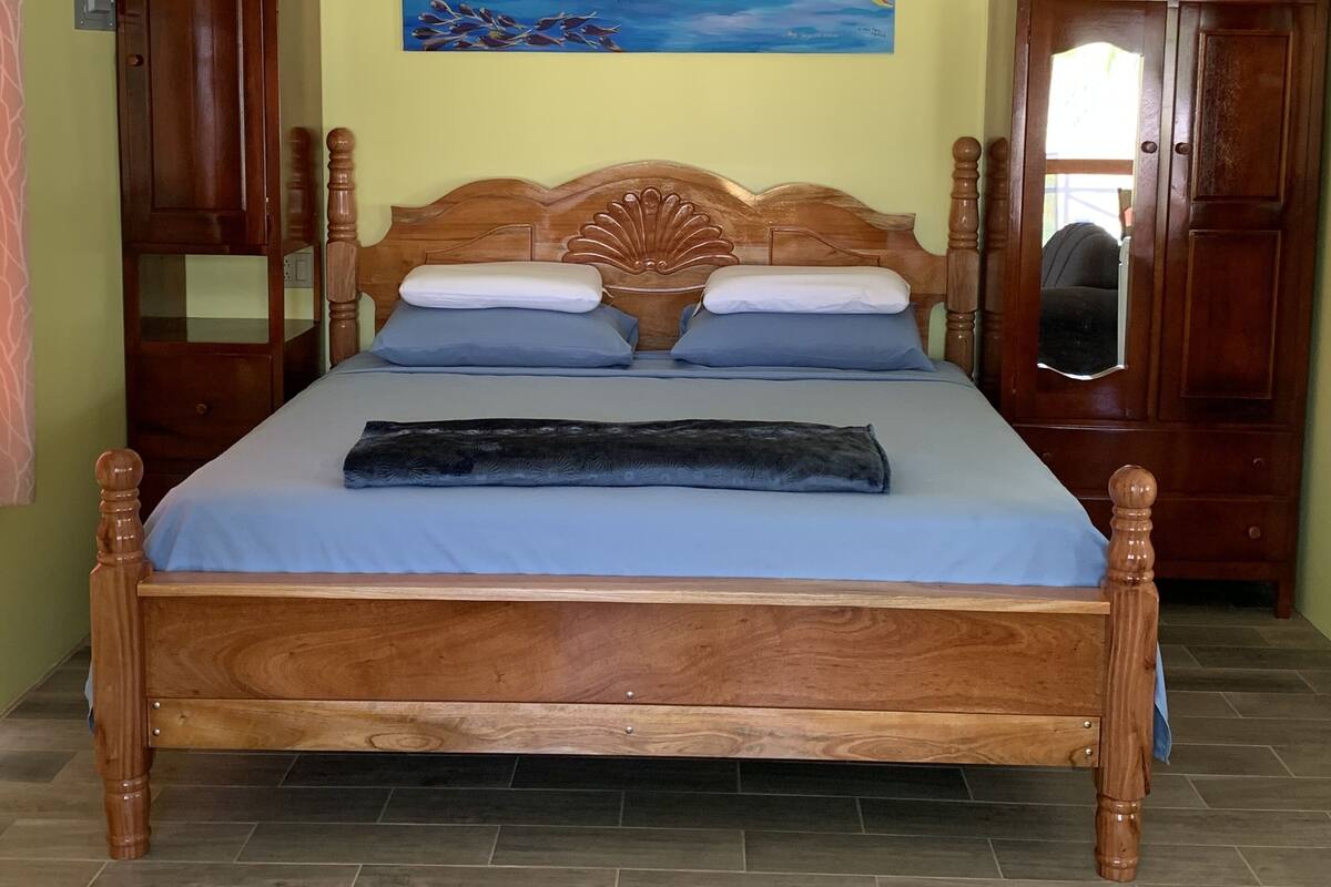 Una cama de madera con cabecera, un cuadro de peces en la pared y armarios de madera.