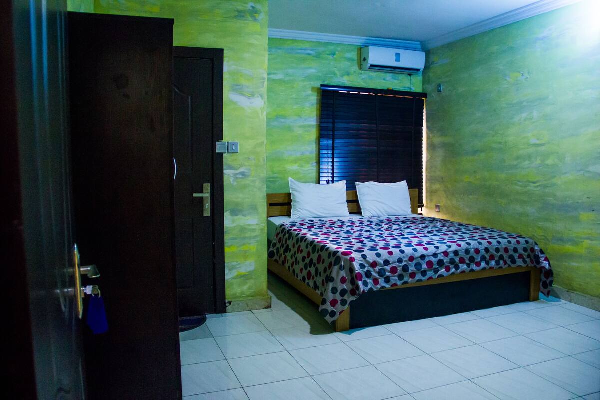 A bedroom with a bed, a door, and a window with blinds.