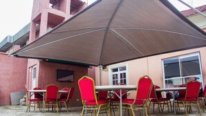 An outdoor patio with a table and chairs under a large umbrella. - Glass House Suites Annex (Lagos)