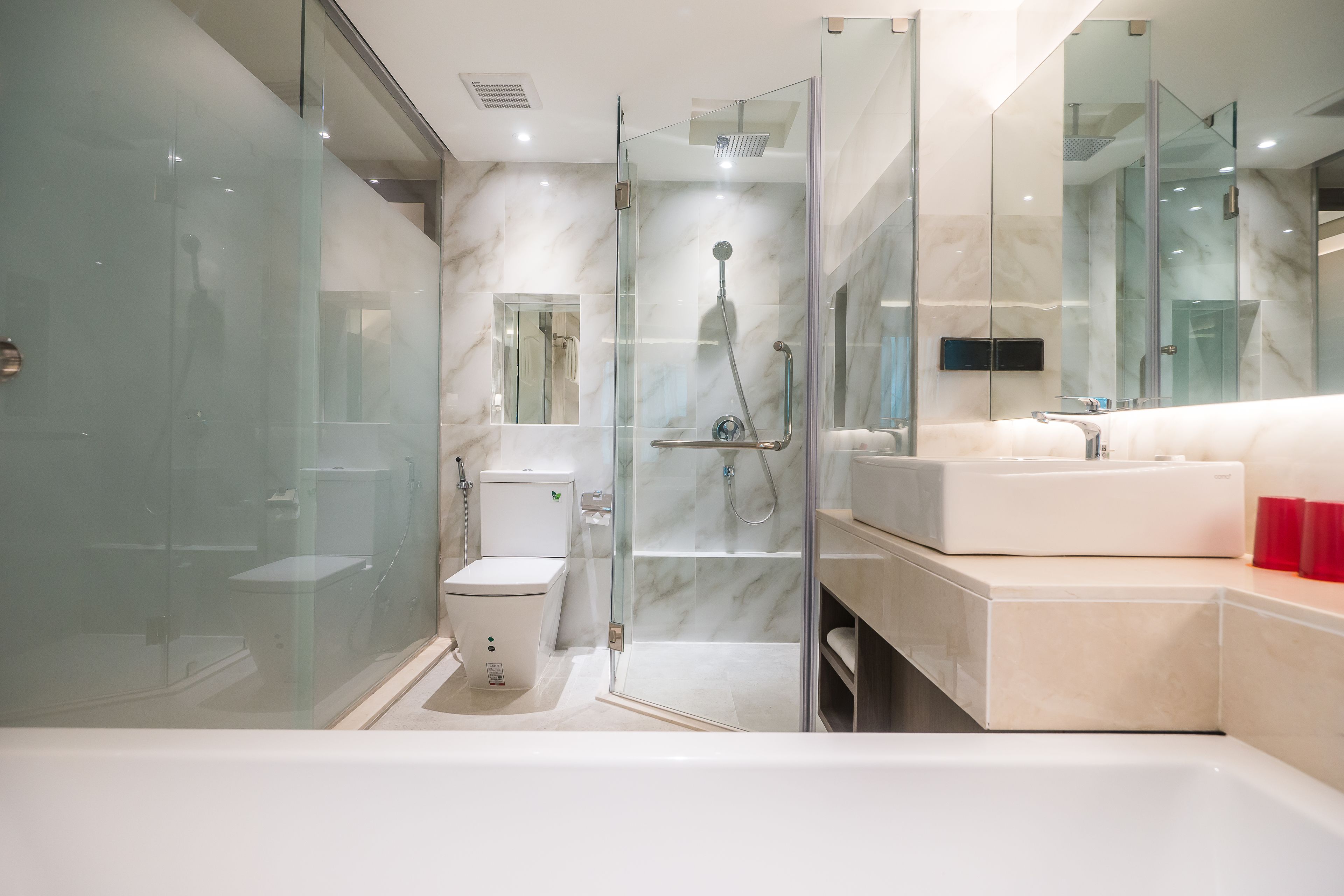 A modern bathroom with a glass-enclosed shower, a toilet, and a large sink.