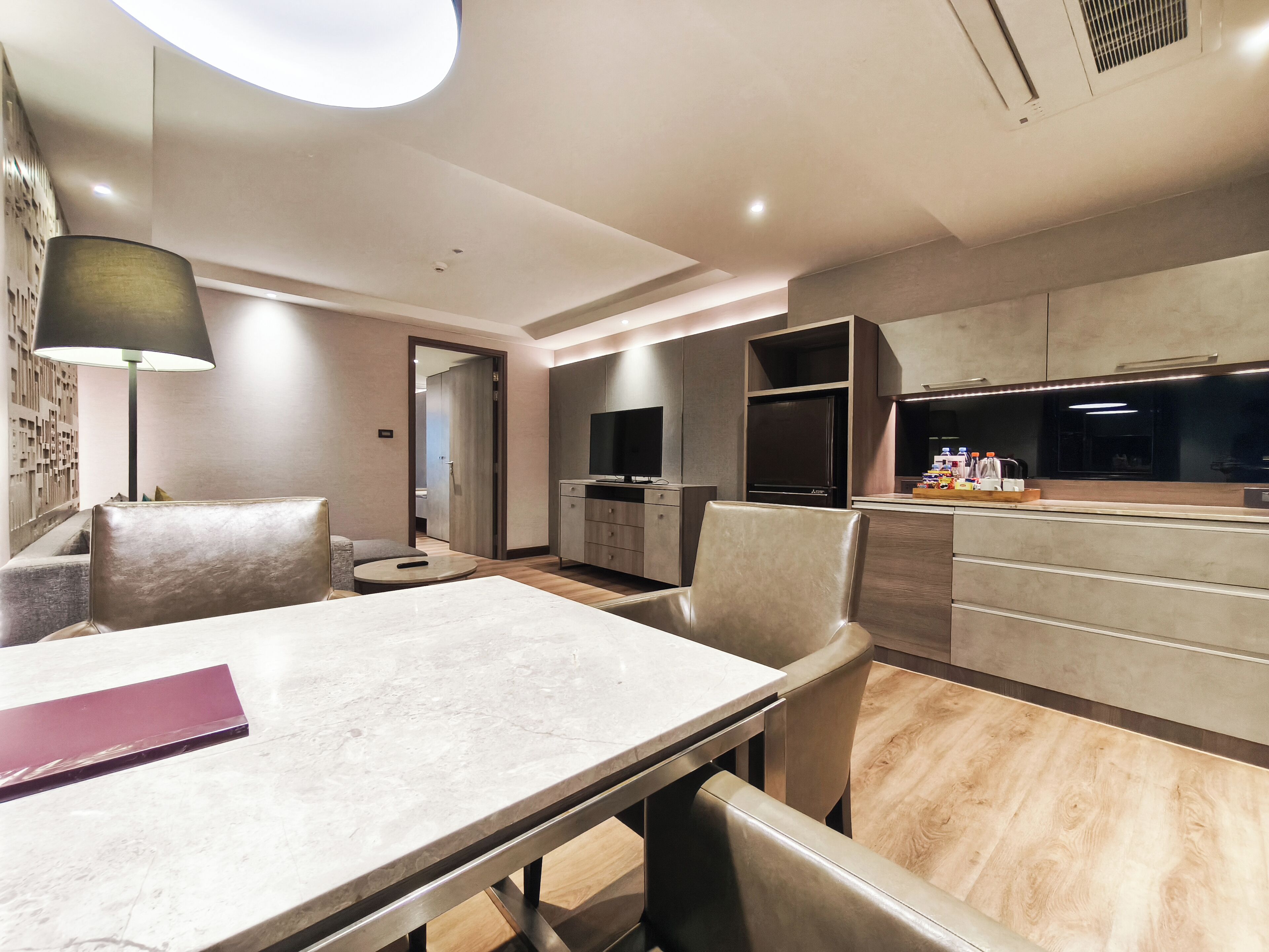 A modern hotel room with a dining area, a kitchen, and a living space.