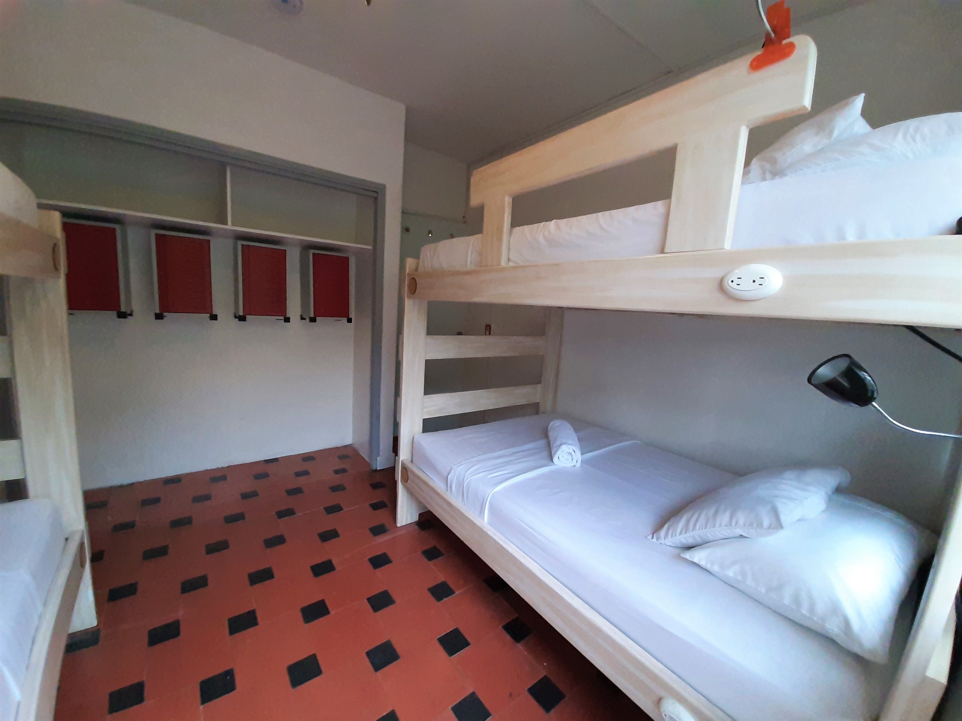 A bunk bed room with a red and black checkered floor, a white bed, and a red wall with three red panels.