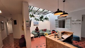 Ein modernes Interieur mit einem Holzbüro, einem grünen Sofa und einer Person, die einen Laptop benutzt.