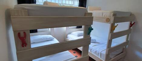 A room with bunk beds, a ceiling fan, and a window with curtains.