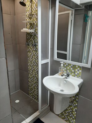 A bathroom with a shower, a sink, and a mirror. - Noah boutique hostels Medellín (Medellín)