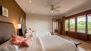 Une chambre d’hôtel avec deux lits, un ventilateur de plafond et une vue sur l’extérieur grâce à une porte coulissante.