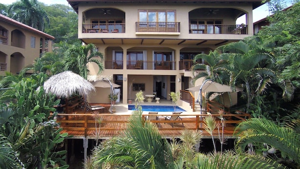 Un hôtel à plusieurs étages doté d’une piscine, entouré d’une végétation tropicale.
