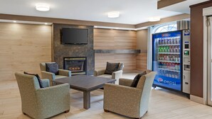 A modern lounge area with a fireplace, comfortable seating, and a Pepsi vending machine. - Quality Inn and Suites Oakville-Mississauga (Oakville)