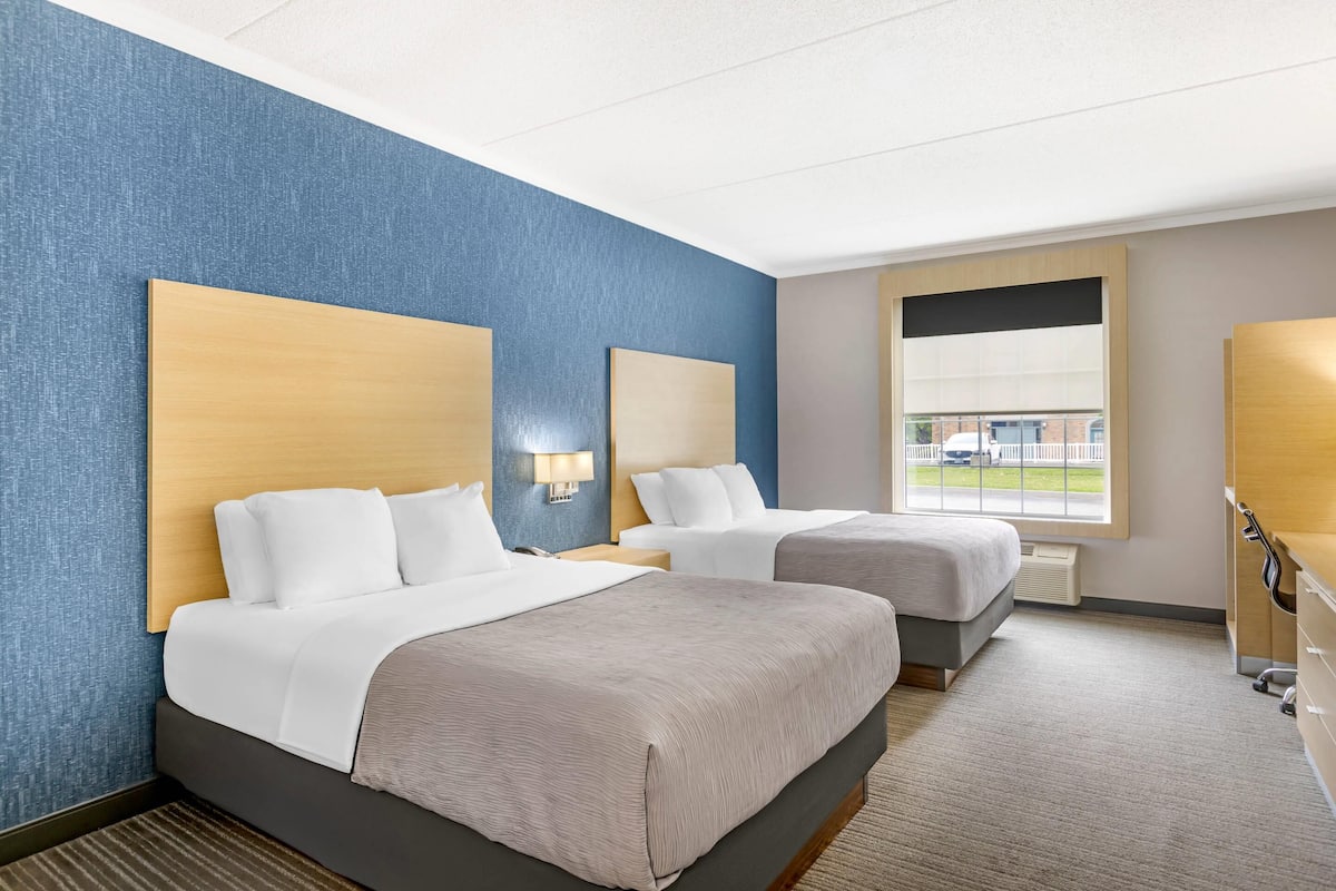 Habitación de hotel con dos camas, un ventanal grande y vistas al exterior.