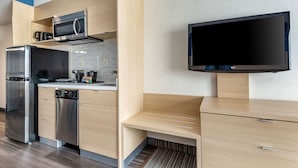 A modern kitchen with stainless steel appliances, a flat-screen TV, and wooden cabinetry. - Quality Inn and Suites Oakville-Mississauga (Oakville)